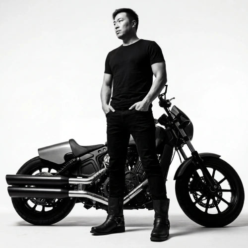 Shek, Founder and Lead Artisan of Ita Bag Co, standing with a motorcycle.
