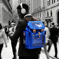Person with a quantum blue Cyberpunk Ita Backpack walking through a busy city street.